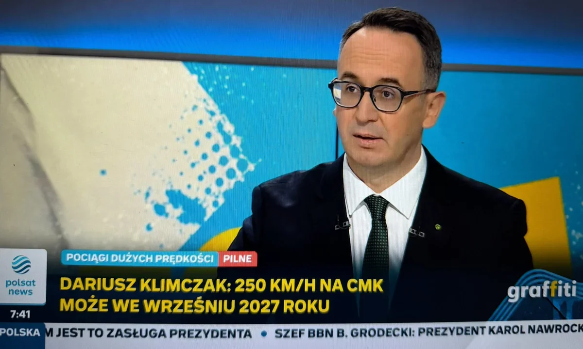 Mężczyzna w garniturze i krawacie występuje w studiu Polsat News, na ekranie za nim grafika z mapą i informacja o prędkości 250 km/h na CMK we wrześniu 2027 rok