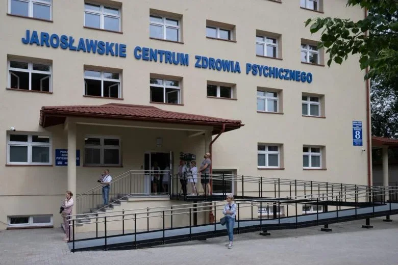 Wejście do Jarosławskiego Centrum Zdrowia Psychicznego, przy którym przebywają kilka osób oraz ekipa z kamerą.