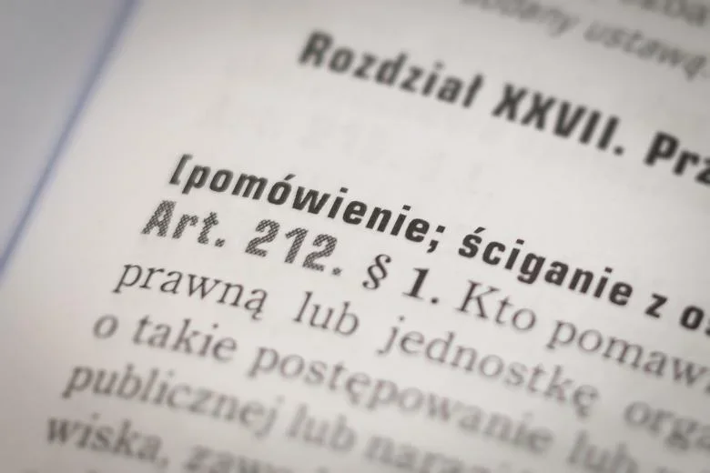 Zbliżenie na fragment polskiego kodeksu karnego z artykułem 212 dotyczącym pomówienia.