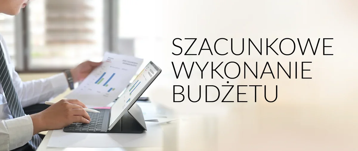 Mężczyzna w koszuli i krawacie analizuje wykresy budżetowe na tablecie i wydruku przy biurku w biurze.