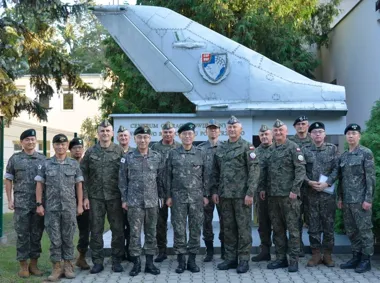 Grupa oficerów wojskowych w mundurach, w tym żołnierze sił zbrojnych Korei Południowej i Polski, pozuje do zdjęcia przed ogonem samolotu z emblematem GOP-DKP pr