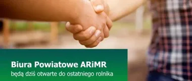 Dwoje ludzi, z których widać fragmenty ubrań i splecione dłonie, stoi na rozmytym tle zewnętrznym.