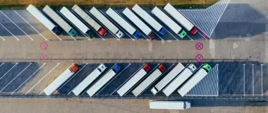 Z lotu ptaka widoczne są zaparkowane ciężarówki na dużym parkingu dla tirów wzdłuż drogi.
