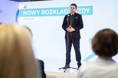 Mężczyzna w garniturze przemawia do publiczności na scenie podczas prezentacji nowego rozkładu jazdy na lata 2026/2027.