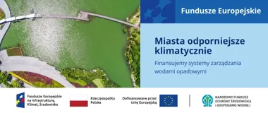Widok z lotu ptaka na zielone jezioro z drewnianym molo, brzegiem z promenadą i zadrzewioną nabrzeżną zabudową miejską.